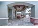 Poolside seating beneath a covered patio area with stone flooring and brick supports at 16768 Sanctuary Dr, Winter Garden, FL 34787