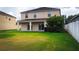 Wide shot of a spacious backyard with lush green grass, a covered patio, and partial fencing at 1748 Thetford Cir, Orlando, FL 32824