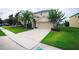 Inviting home exterior featuring a manicured lawn, lush landscaping, and a spacious driveway leading to a garage at 1748 Thetford Cir, Orlando, FL 32824