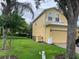Side view of a yellow two-story home featuring a well-maintained lawn, a garage, and AC unit at 17614 Woodcrest Way, Clermont, FL 34714