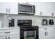 Close up of stainless steel microwave and oven with white cabinets and marble backsplash at 17614 Woodcrest Way, Clermont, FL 34714