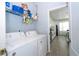 Bright laundry area with white appliances and shelving connects to the modern kitchen at 17614 Woodcrest Way, Clermont, FL 34714