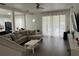 Bright living room with a comfortable sectional sofa, sheer curtains, and wood-look floors, offering a view of the pool at 17614 Woodcrest Way, Clermont, FL 34714