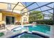 Inviting screened-in pool and spa area with a dining table, chairs and grill outside at 17614 Woodcrest Way, Clermont, FL 34714