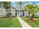 Charming two-story condo with light-blue siding, a well-manicured lawn, and mature trees creating a serene outdoor space at 2020 Royal Bay Blvd # 91, Kissimmee, FL 34746
