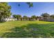 Large grassy backyard with a partial view of the house, nearby building, and fencing at 2222 Catherine St, Kissimmee, FL 34741