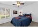 Cozy bedroom with plush carpeting, a ceiling fan, and a bright window overlooking a pleasant street view at 2344 Whispering Maple Dr., Orlando, FL 32837