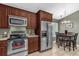 Well-equipped kitchen boasting stainless appliances, dark wood cabinets, tile floors, and adjacent dining area at 2344 Whispering Maple Dr., Orlando, FL 32837