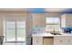 Bright kitchen features white cabinets, modern appliances, quartz countertops, and sliding glass door to the backyard at 3044 Camino Real S Dr, Kissimmee, FL 34744
