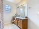 Bright bathroom features tiled floor, large mirror, vanity, and window at 348 Sigmund Loop, Davenport, FL 33837