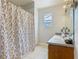Bright bathroom features butterfly shower curtain, tiled floor, vanity and window at 348 Sigmund Loop, Davenport, FL 33837