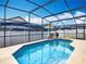 A screened-in pool sparkles on a sunny day, surrounded by mature landscaping at 348 Sigmund Loop, Davenport, FL 33837