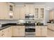 Bright kitchen with stainless steel appliances and cream colored cabinets and black countertop at 3868 Whitewood Ct, Oviedo, FL 32766