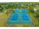 Aerial view of four well-maintained tennis courts surrounded by lush greenery and homes in the distance at 3868 Whitewood Ct, Oviedo, FL 32766