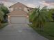 Two-story home featuring a two-car garage, a driveway, and a palm tree in the yard at 437 Bridgewater Court, Kissimmee, FL 34758