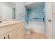 This bathroom features a blue tiled shower-tub, a light vanity, and tan tile floors at 450 S Buena Vista Ave, Orlando, FL 32835