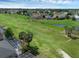 Aerial view showcasing a lush green lawn, mature trees, pond, and neighborhood, highlighting community amenities at 468 Jaybee Ave, Davenport, FL 33897