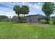 Expansive backyard featuring a screened lanai and lush green lawn with mature palm trees and landscaping at 468 Jaybee Ave, Davenport, FL 33897