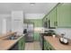 Kitchen with modern stainless steel appliances, bright green cabinets, and neutral countertops at 468 Jaybee Ave, Davenport, FL 33897
