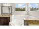 Bright bathroom showcasing a soaking tub beneath a window, granite countertops, and elegant cabinetry at 5032 Beach River Rd, Windermere, FL 34786