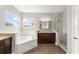 Bathroom featuring a soaking tub, granite countertops, wood flooring, glass enclosed shower, and natural light from a window at 5032 Beach River Rd, Windermere, FL 34786
