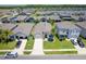 Aerial front elevation of the home featuring a well manicured lawn, mature palms and a two car garage at 5306 Rochester Pl, St Cloud, FL 34771