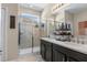 Modern bathroom featuring double sinks, a glass-enclosed shower, and neutral tile at 5306 Rochester Pl, St Cloud, FL 34771