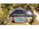Aerial view of a home's backyard featuring solar panels, a pool with a screened enclosure and outdoor seating at 6917 Roman Ct, Clermont, FL 34714
