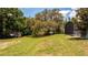 Private backyard with mature shade trees and well maintained lawn next to a screened lanai at 6917 Roman Ct, Clermont, FL 34714