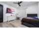This bedroom features a gray bed frame, hardwood floors, a black ceiling fan, and a large TV for a modern design at 6917 Roman Ct, Clermont, FL 34714