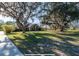 View of the home's front exterior and yard with mature trees, driveway, and walkway at 6917 Roman Ct, Clermont, FL 34714