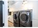 Modern laundry room with gray washer and dryer, white cabinets, pendant lighting, and wood-look flooring at 6917 Roman Ct, Clermont, FL 34714