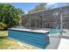 Outdoor kitchen with granite countertop and stainless steel grill near a screened-in pool at 6917 Roman Ct, Clermont, FL 34714