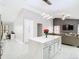 Modern kitchen with center island, white quartz counters and stainless appliances, connected to the living room at 7974 Village Green Rd, Orlando, FL 32818