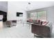Modern living room with grey plush seating, contemporary chandelier, and sleek white tile flooring at 7974 Village Green Rd, Orlando, FL 32818