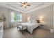 Serene main bedroom featuring tray ceilings, light wood floors, and a large window with natural light at 8067 Crushed Pepper Ave, Orlando, FL 32817