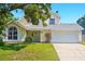 Charming yellow two-story home featuring a well-maintained front yard, arched window, and a two-car garage at 879 Matt Ln, Port Orange, FL 32127