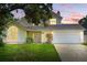 Charming yellow two-story home featuring a well-maintained front yard, arched window, and a two-car garage at 879 Matt Ln, Port Orange, FL 32127