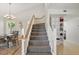 Open staircase with carpet treads and white wood railing, adjacent to a dining area and shelving unit at 879 Matt Ln, Port Orange, FL 32127