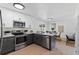Well-lit kitchen with stainless steel appliances, gray cabinets, quartz countertop and a view to the dining area at 9987 Triple Crown Cir, Orlando, FL 32825