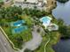 Aerial view of neighborhood amenities, including a pool, tennis courts, and a clubhouse by the water at 10143 Pink Carnation Ct, Orlando, FL 32825