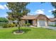 Charming single-story home featuring a well-manicured lawn and inviting front entrance with a tree at 10143 Pink Carnation Ct, Orlando, FL 32825