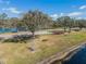 Scenic view of a park bench by the lakeside surrounded by trees, lush grass, and vibrant flowerbeds under a blue sky at 10143 Pink Carnation Ct, Orlando, FL 32825