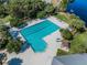 Aerial view of a community pool with lap lanes, lounge chairs, and palm trees near a lake at 10143 Pink Carnation Ct, Orlando, FL 32825