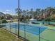 Aerial view of tennis courts with a shaded seating area, surrounded by trees and greenery at 10143 Pink Carnation Ct, Orlando, FL 32825