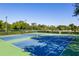 A view of the blue tennis courts, surrounded by a green fence and bright green trees at 125 W Wyndham Ct, Longwood, FL 32779