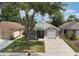 Single-story home with mature trees, a driveway, and landscaping at 13169 Odyssey Lake Way, Orlando, FL 32826