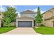 Two-story home featuring a neutral exterior, gray two-car garage door, and a well-maintained lawn at 14208 Shocklach Dr, Winter Garden, FL 34787