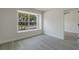 Bright bedroom with gray wood floors, fresh paint, and a view to the outside through a large window at 1633 Pinehurst Dr, Casselberry, FL 32707