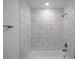 This white tiled tub and shower combo features bronze fixtures and provides a relaxing bathing experience at 2260 Suanne Ave, Eustis, FL 32726